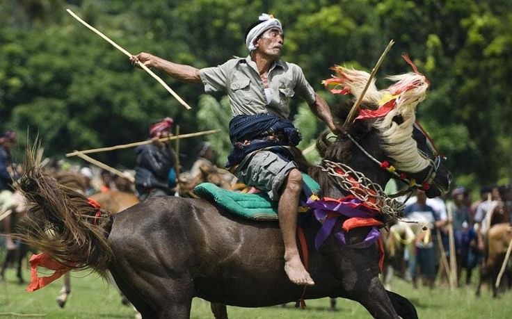 Sumba local fighting on horseback at the pasola festival, showcasing traditional culture in harmony with sustainable tourism. Sumba local fighting on horseback at the pasola festival, showcasing traditional culture in harmony with sustainable tourism.
