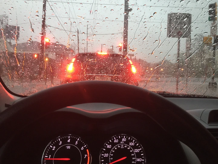 Passenger inside a car looking through the windshield while rain is coming down and the wipers are on Passenger inside a car looking through the windshield while rain is coming down and the wipers are on