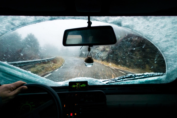 person in a car driving in the snow looking through the windshield, while it's snowing. person in a car driving in the snow looking through the windshield, while it's snowing.