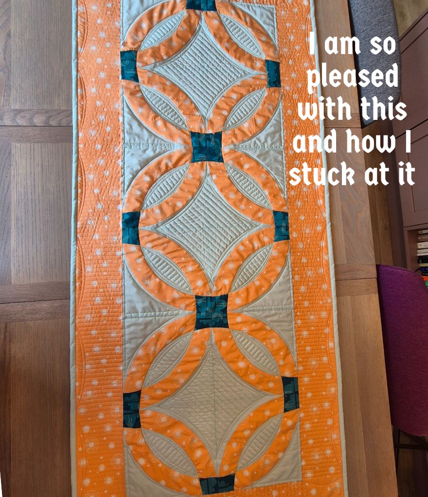 Finished Double Wedding Ring quilt on a table, showing colourful arcs and detailed quilting, Finished Double Wedding Ring quilt on a table, showing colourful arcs and detailed quilting,