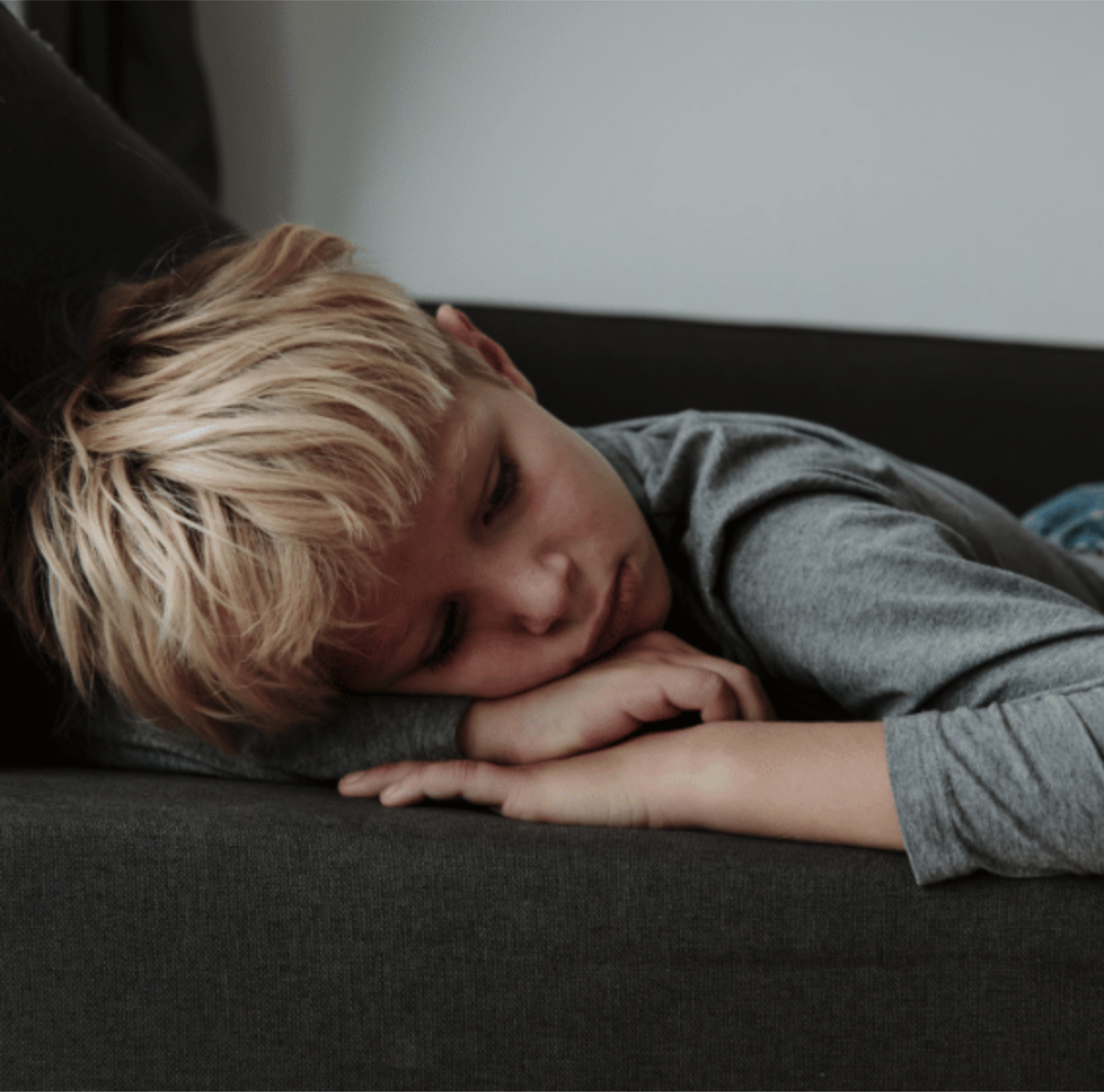 Unhappy child laying on couch with eyes closed