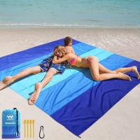 Image of a large, lightweight beach blanket spread out on sand, with anchor stakes visible at the corners. Image of a large, lightweight beach blanket spread out on sand, with anchor stakes visible at the corners.