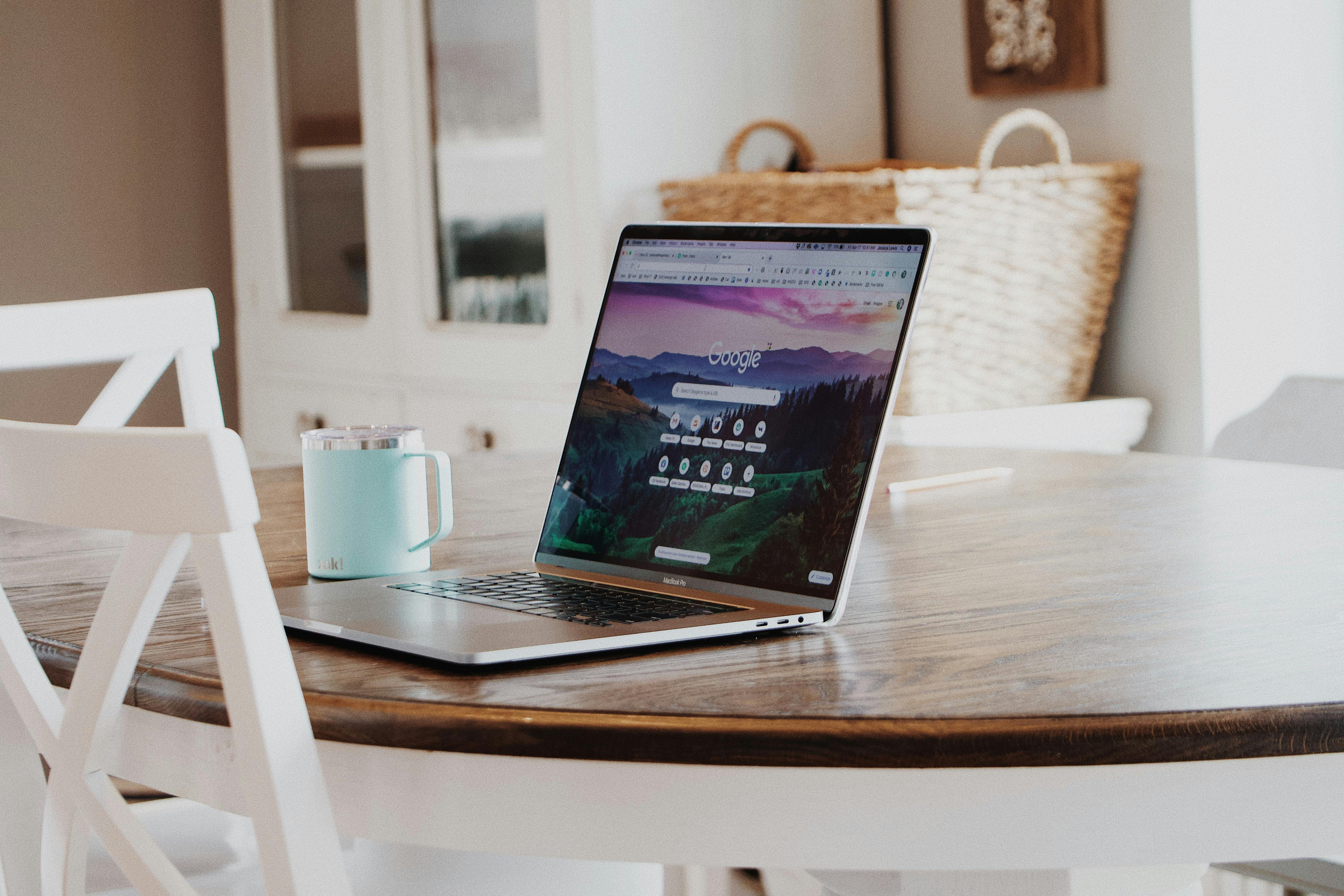 A laptop on the table with a mug beside A laptop on the table with a mug beside