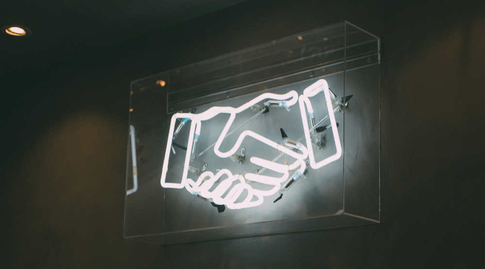 image of a neon sign showing the facebook handshake icon