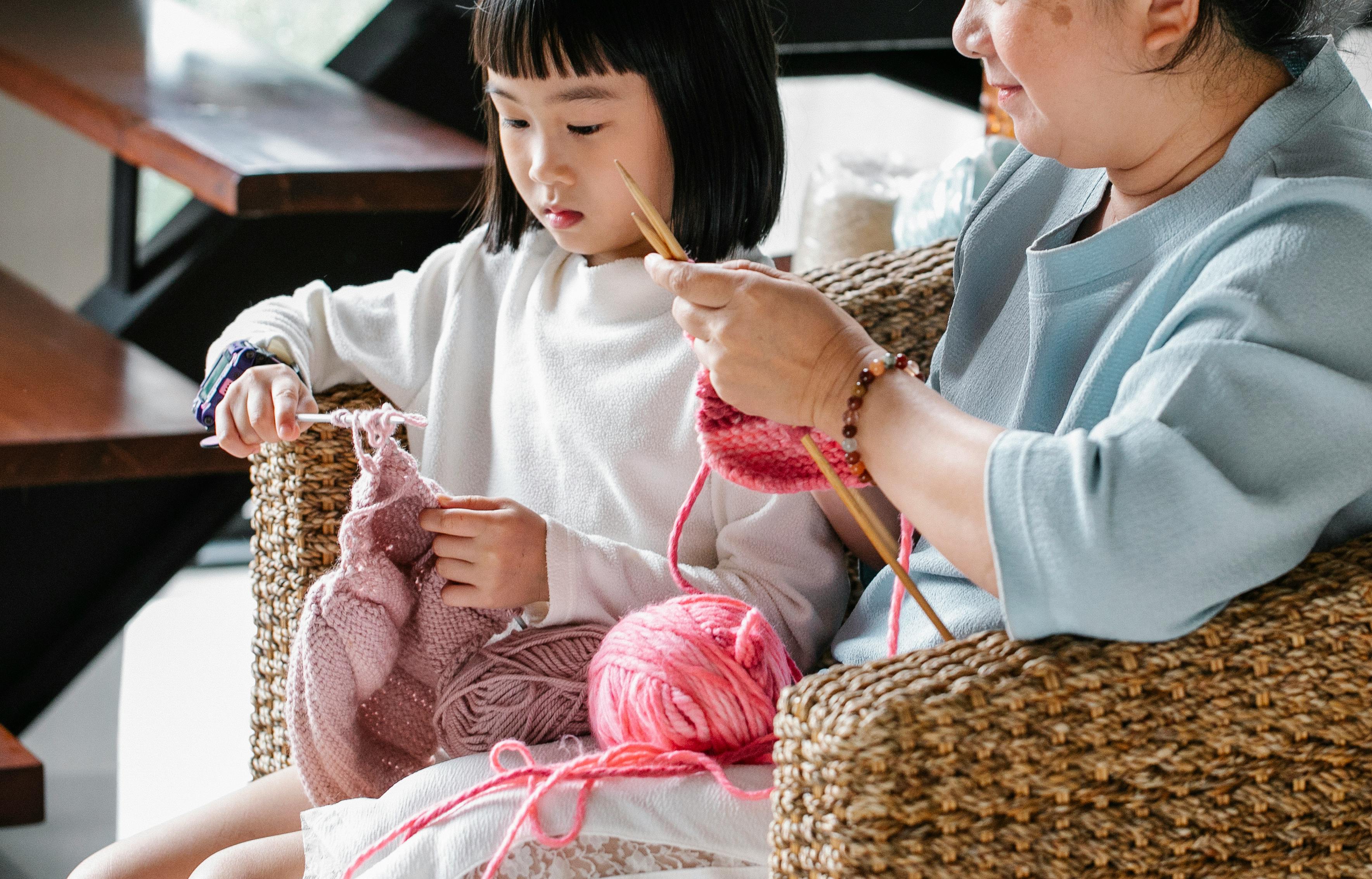 Young child being taught how to knit but her Grandma
