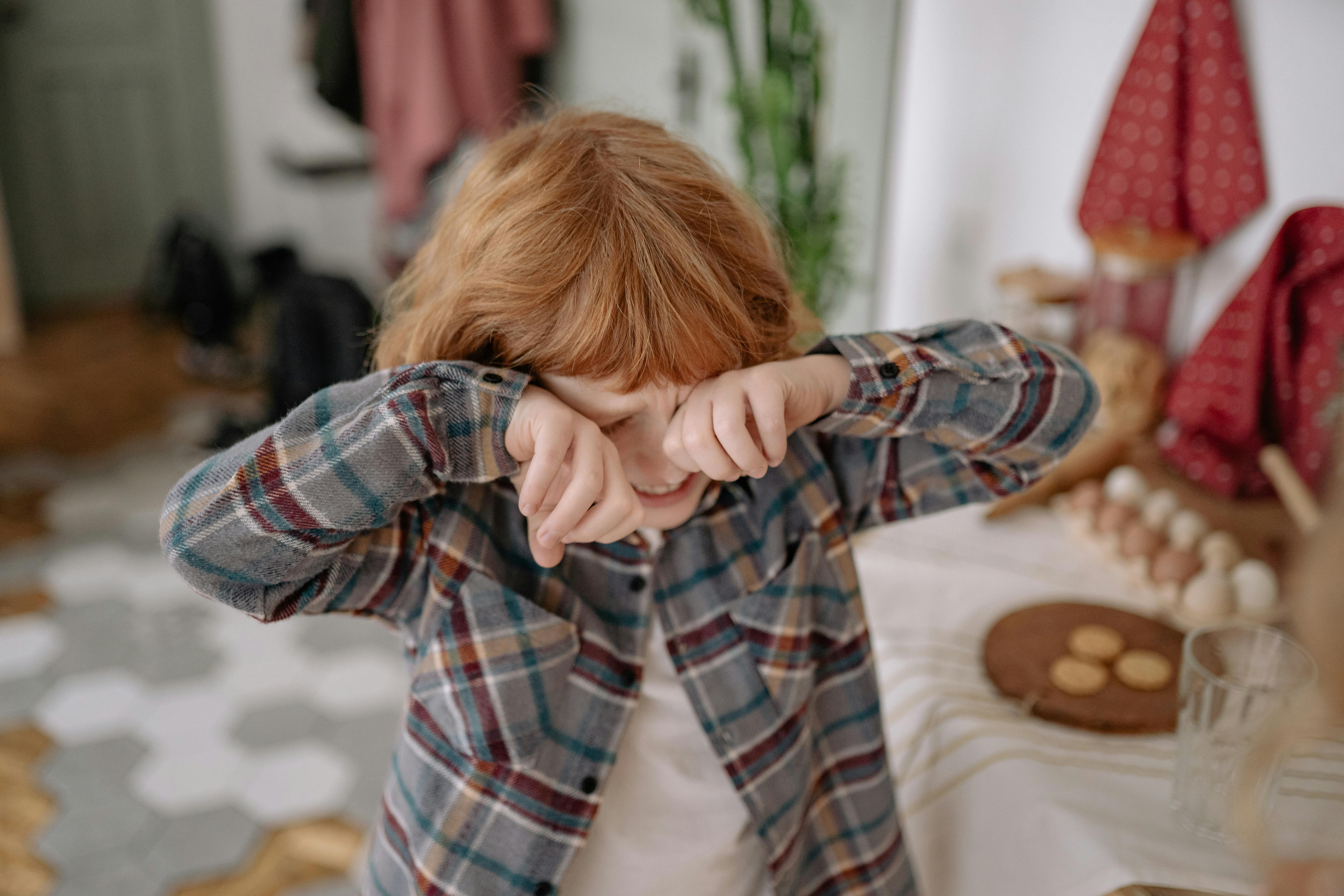 Young boy crying and wiping his eyes in the living room