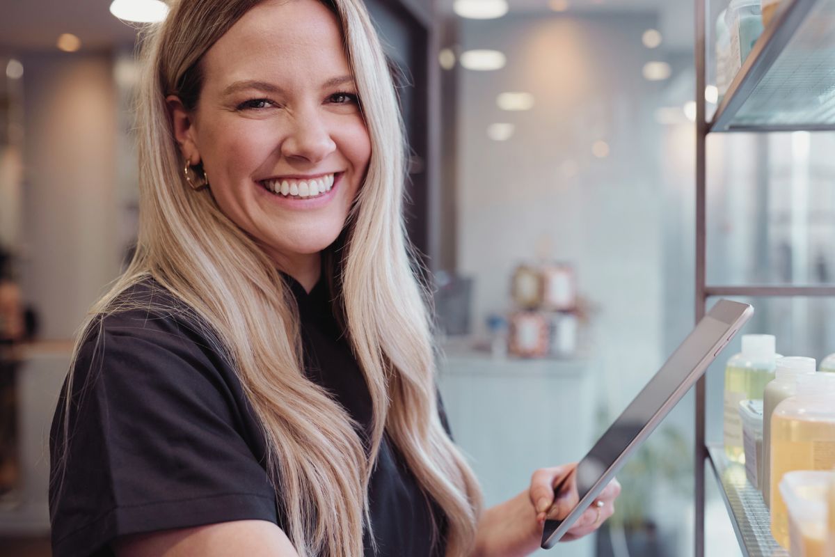 a light haired woman smiling at the camera while taking stock of her inventory a light haired woman smiling at the camera while taking stock of her inventory
