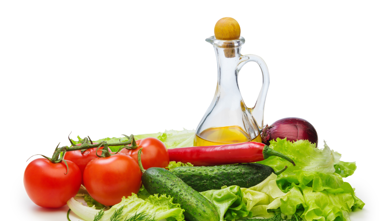 Fresh vegetables with a glass bottle of olive oil on white background, including tomatoes, cucumber, lettuce, and red onion. Fresh vegetables with a glass bottle of olive oil on white background, including tomatoes, cucumber, lettuce, and red onion.