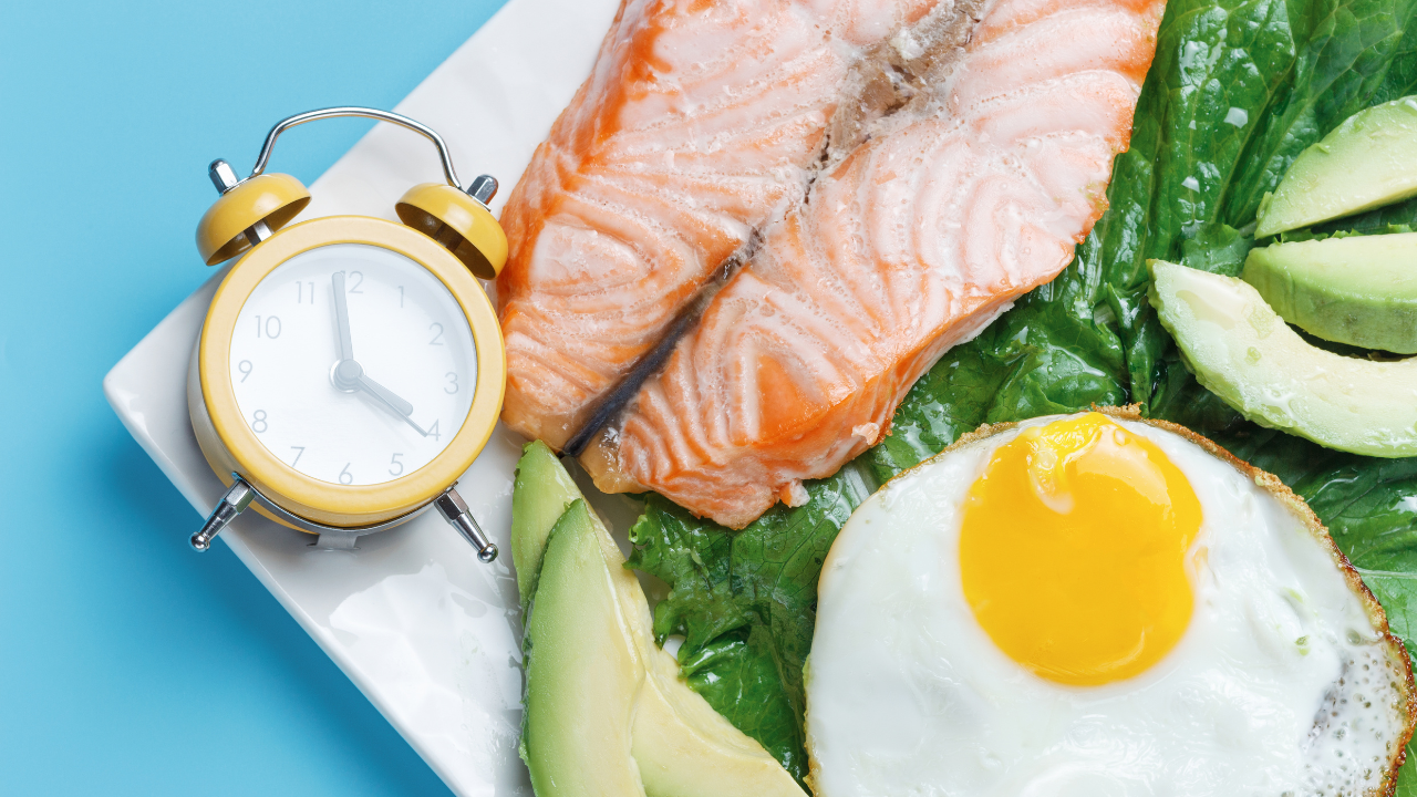 Healthy keto breakfast with grilled salmon, avocado, fried egg, and lettuce, with a yellow alarm clock. Healthy keto breakfast with grilled salmon, avocado, fried egg, and lettuce, with a yellow alarm clock.