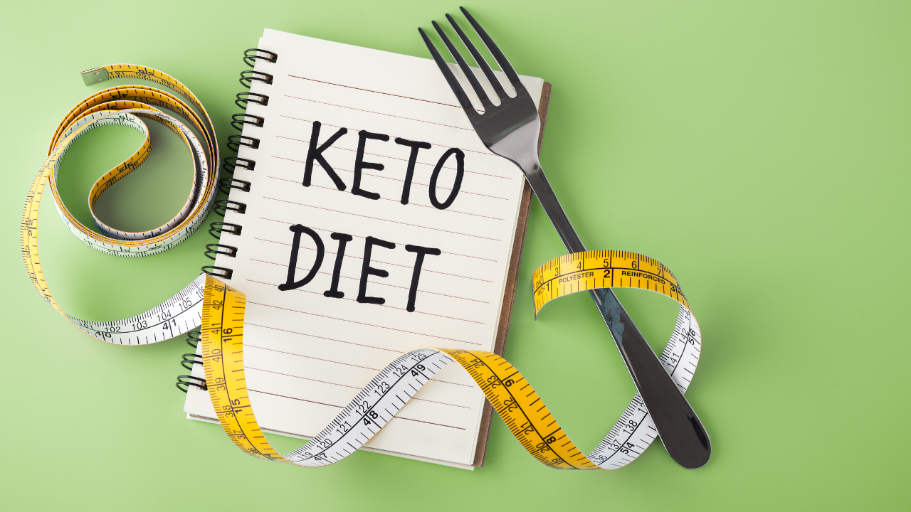 Notebook with 'Keto Diet' written on it surrounded by a measuring tape and fork, representing weight loss and keto lifestyle. Notebook with 'Keto Diet' written on it surrounded by a measuring tape and fork, representing weight loss and keto lifestyle.