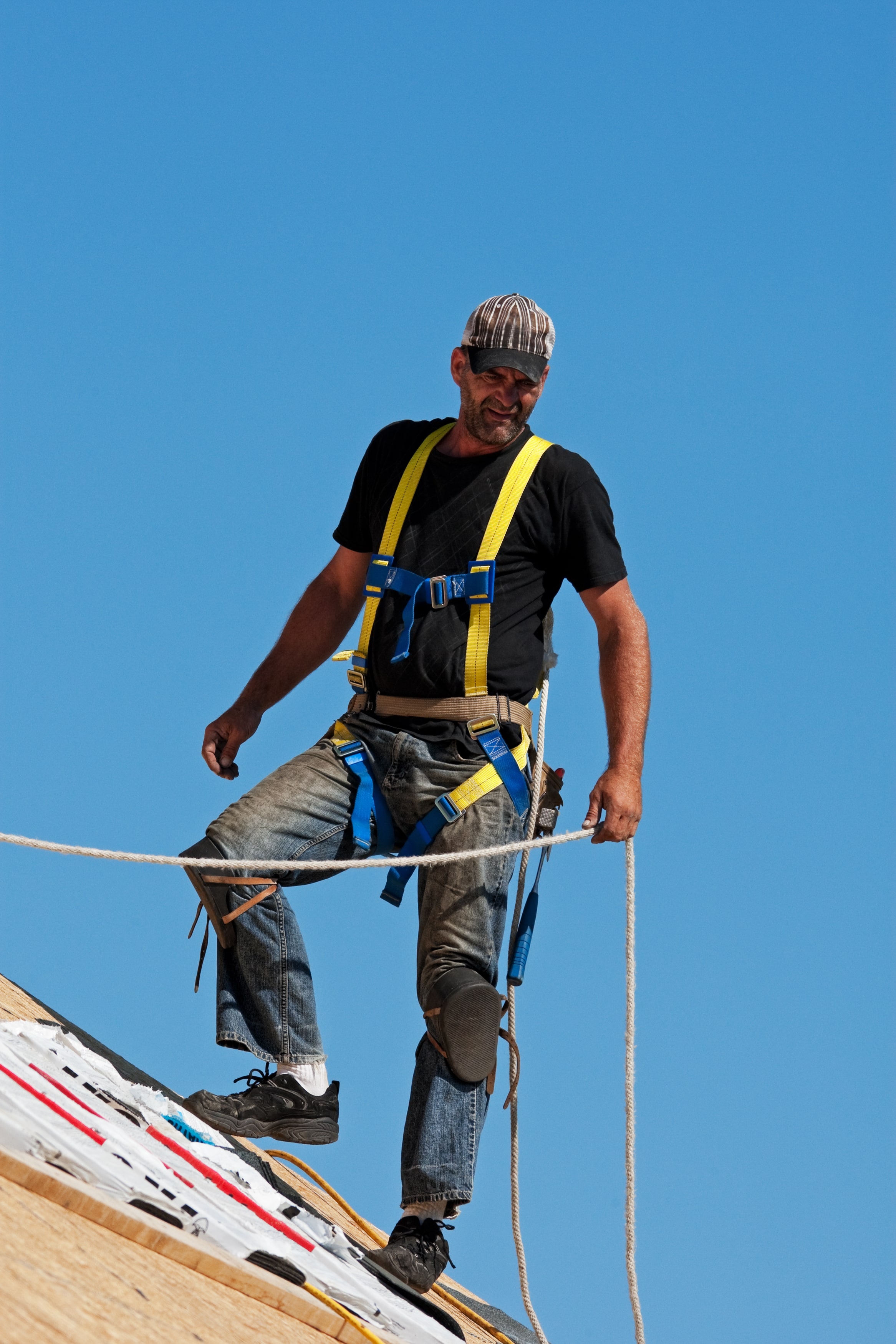 Northern Texas Roofing Contractor - Roofer with safety harness shingling a roof with a steep pitch.jpg