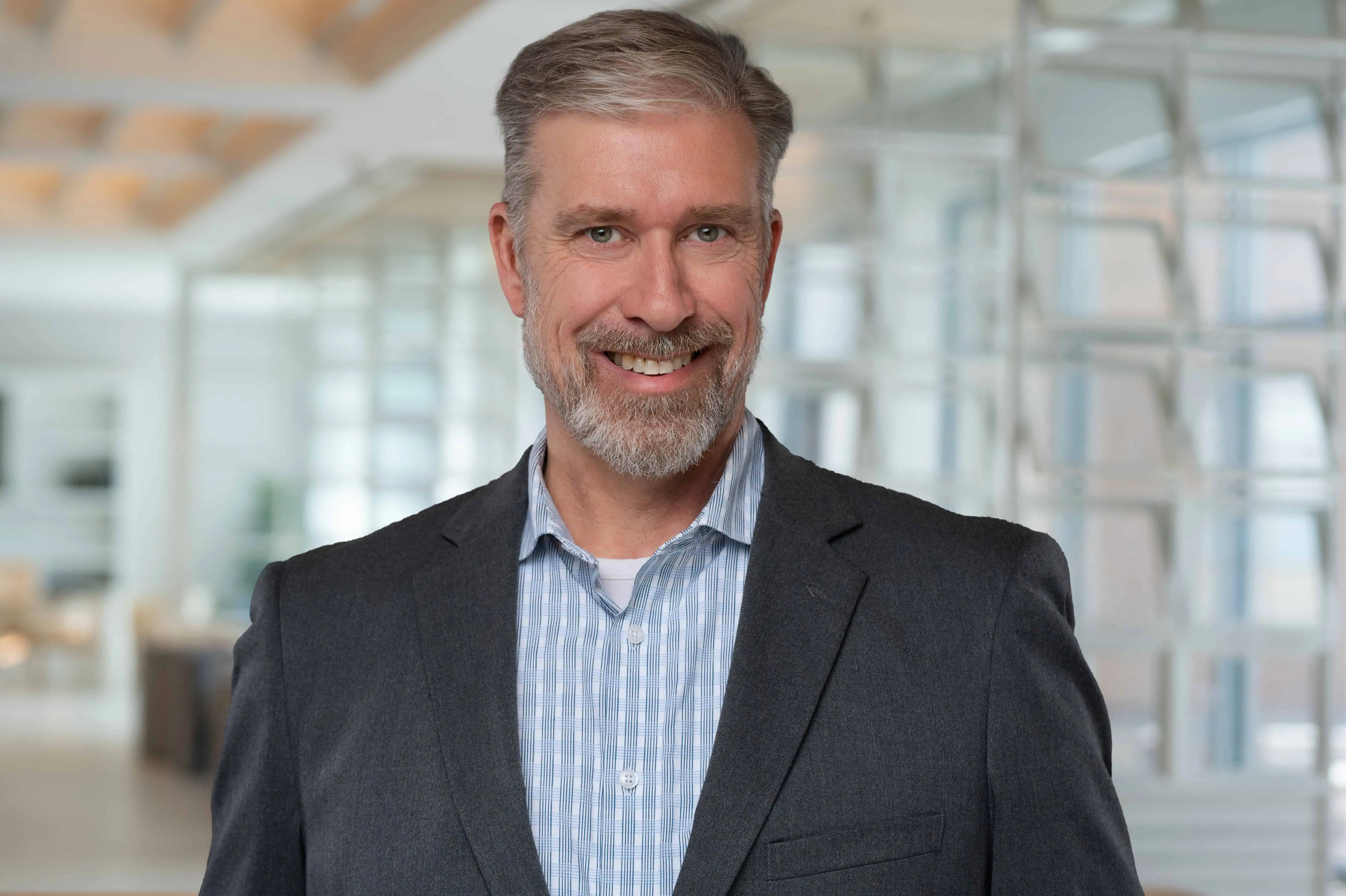 Headshot image of a male in an office with a lot of windows Headshot image of a male in an office with a lot of windows