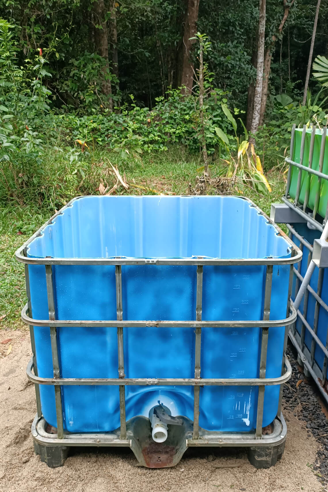 A blue-painted aquaponic fish tank on a bed of sand A blue-painted aquaponic fish tank on a bed of sand