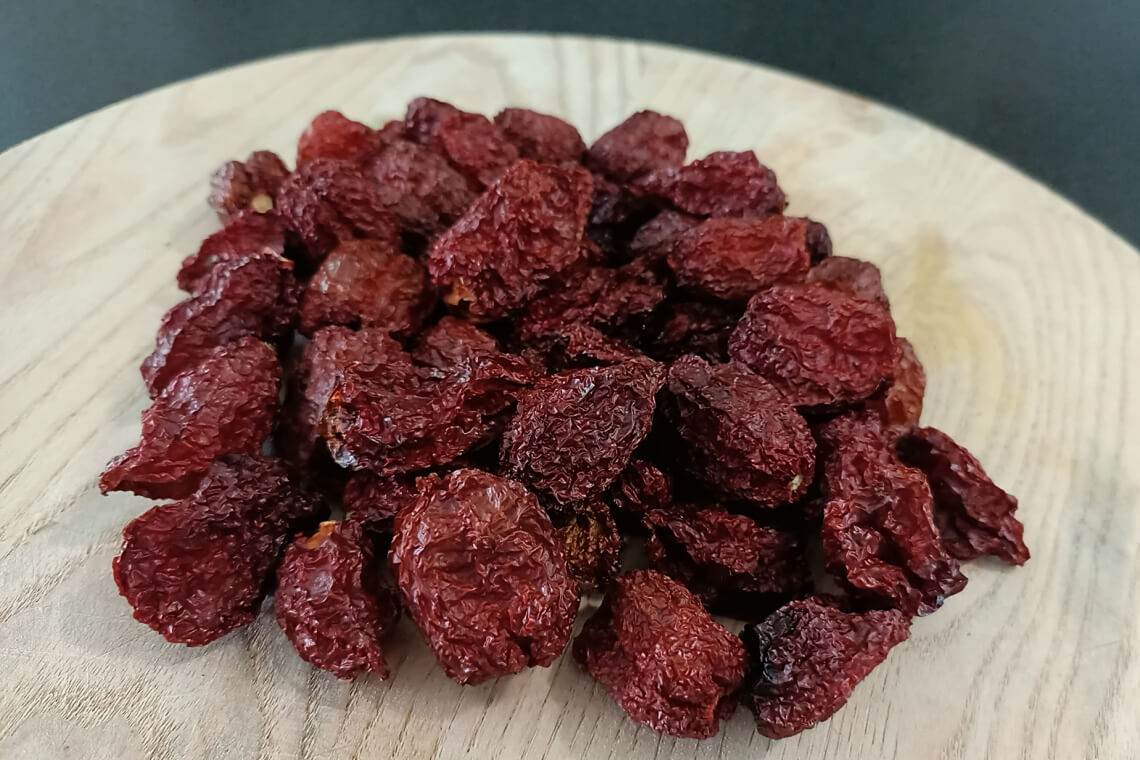 A pile of dried whole Chocolate Bhutlah peppers with dark brown, wrinkled skin on a wooden chopping board A pile of dried whole Chocolate Bhutlah peppers with dark brown, wrinkled skin on a wooden chopping board