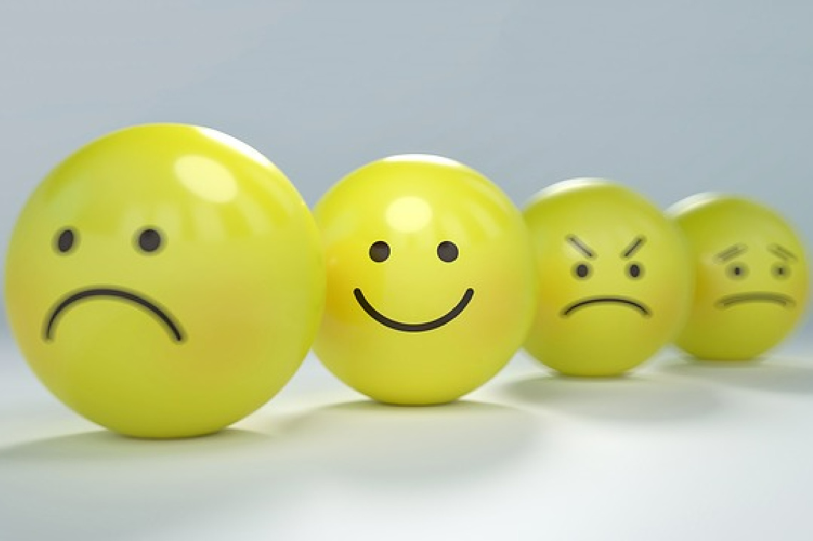 A row of yellow balls with faces, featuring a central smiley face and blurred, sad and angry faces on the surrounding balls, representing different states of mental health. A row of yellow balls with faces, featuring a central smiley face and blurred, sad and angry faces on the surrounding balls, representing different states of mental health.