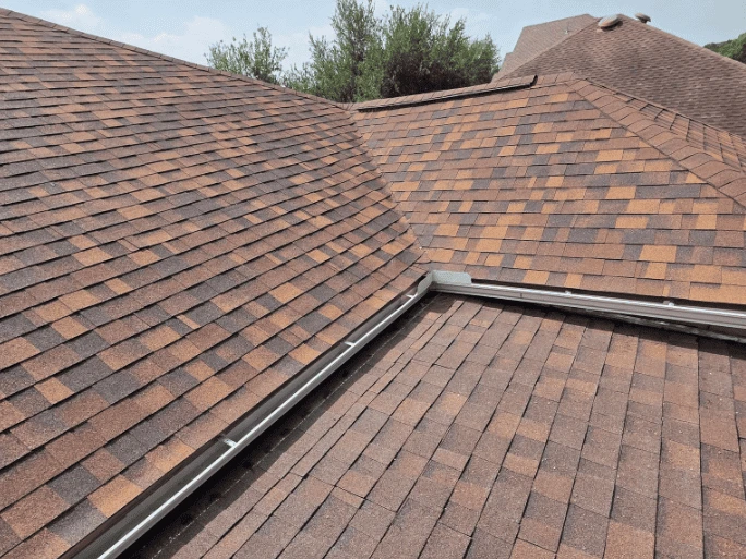 a roof undergoing remodeling with new asphalt shingles and a gutter system.