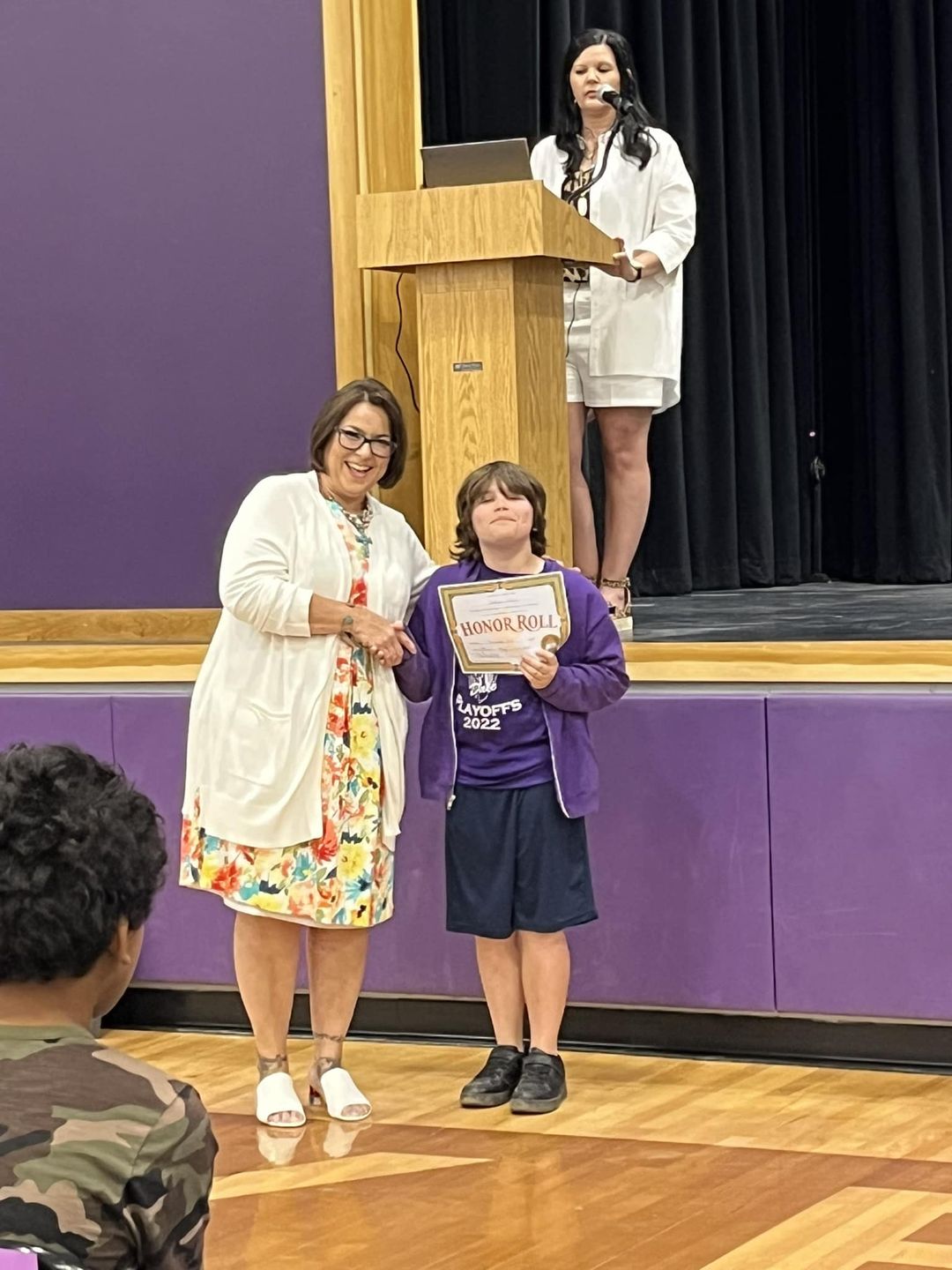 boy accepting award from principal in front of school stage