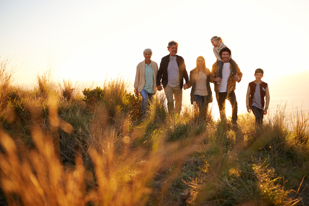 Family walking through a field with very tall grass at sunset