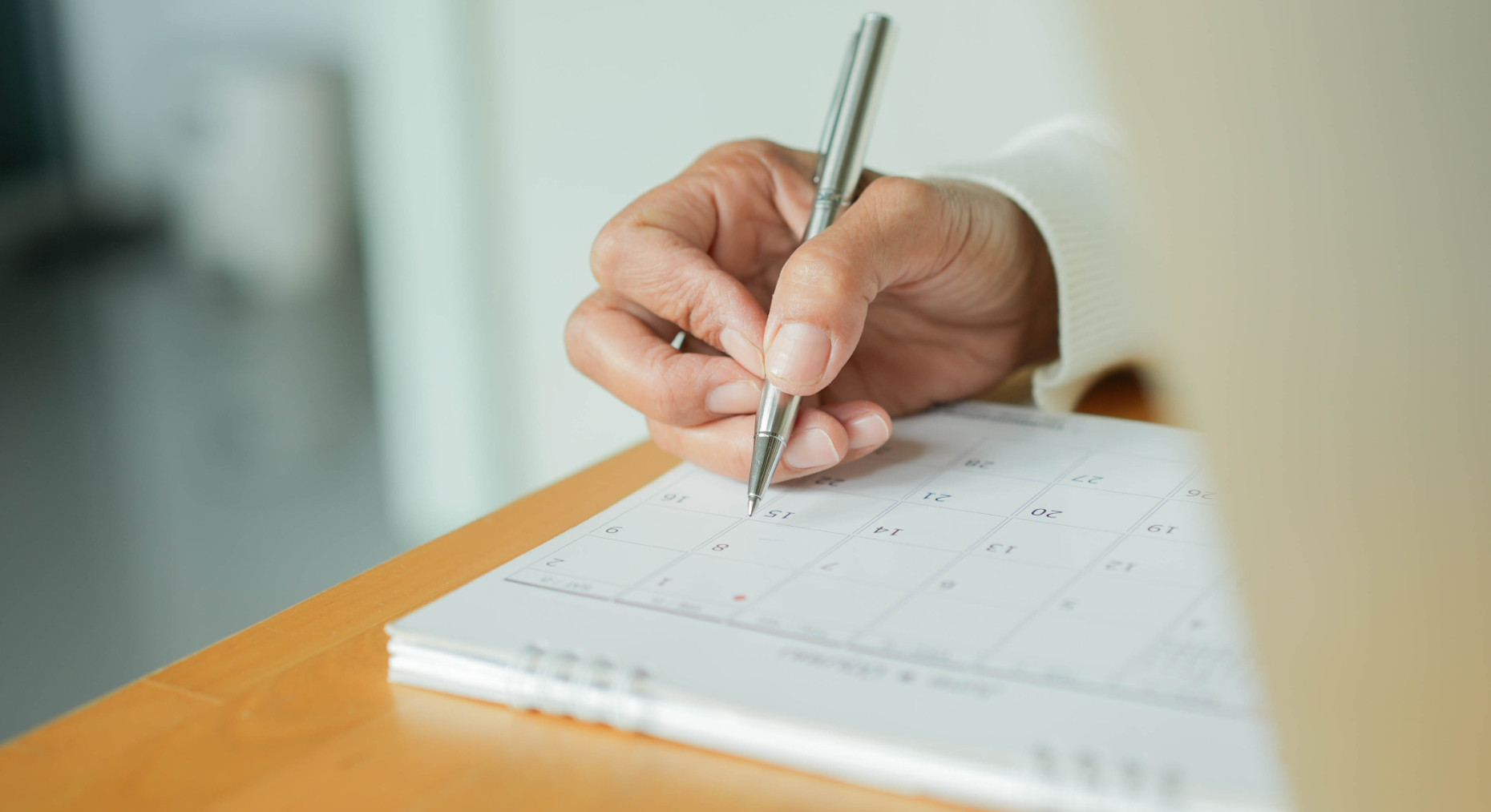 Person writes in a paper day planner to add an appointment for a therapy session