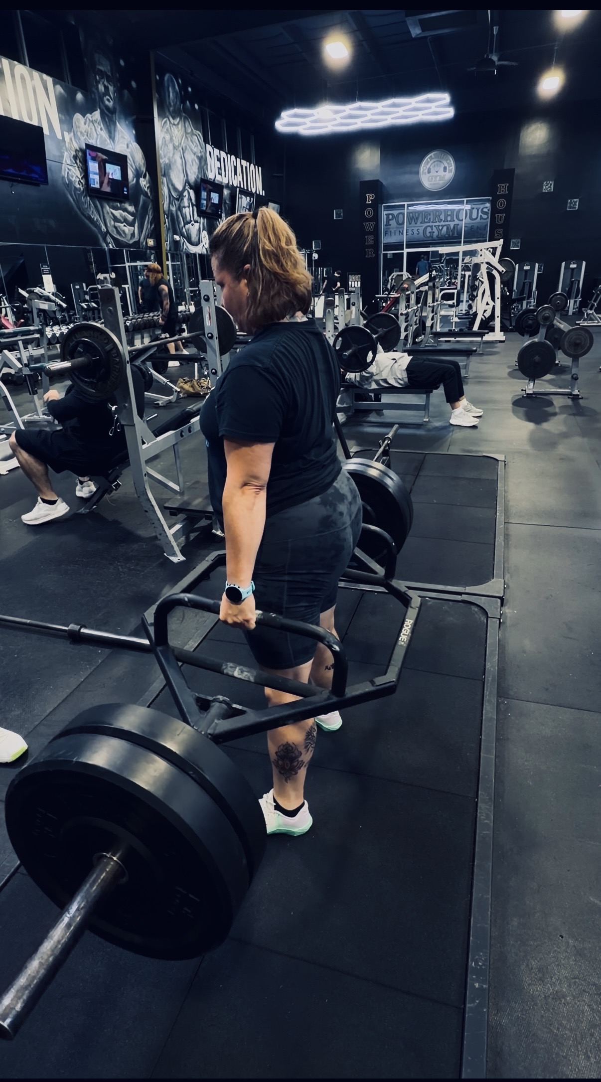 A woman performing a trap bar deadlift in a gym, demonstrating proper lifting technique and strength training form. The image represents confidence, power, and functional fitness after 40, showing how proper deadlift mechanics build muscle, protect the lower back, and promote longevity and independence.