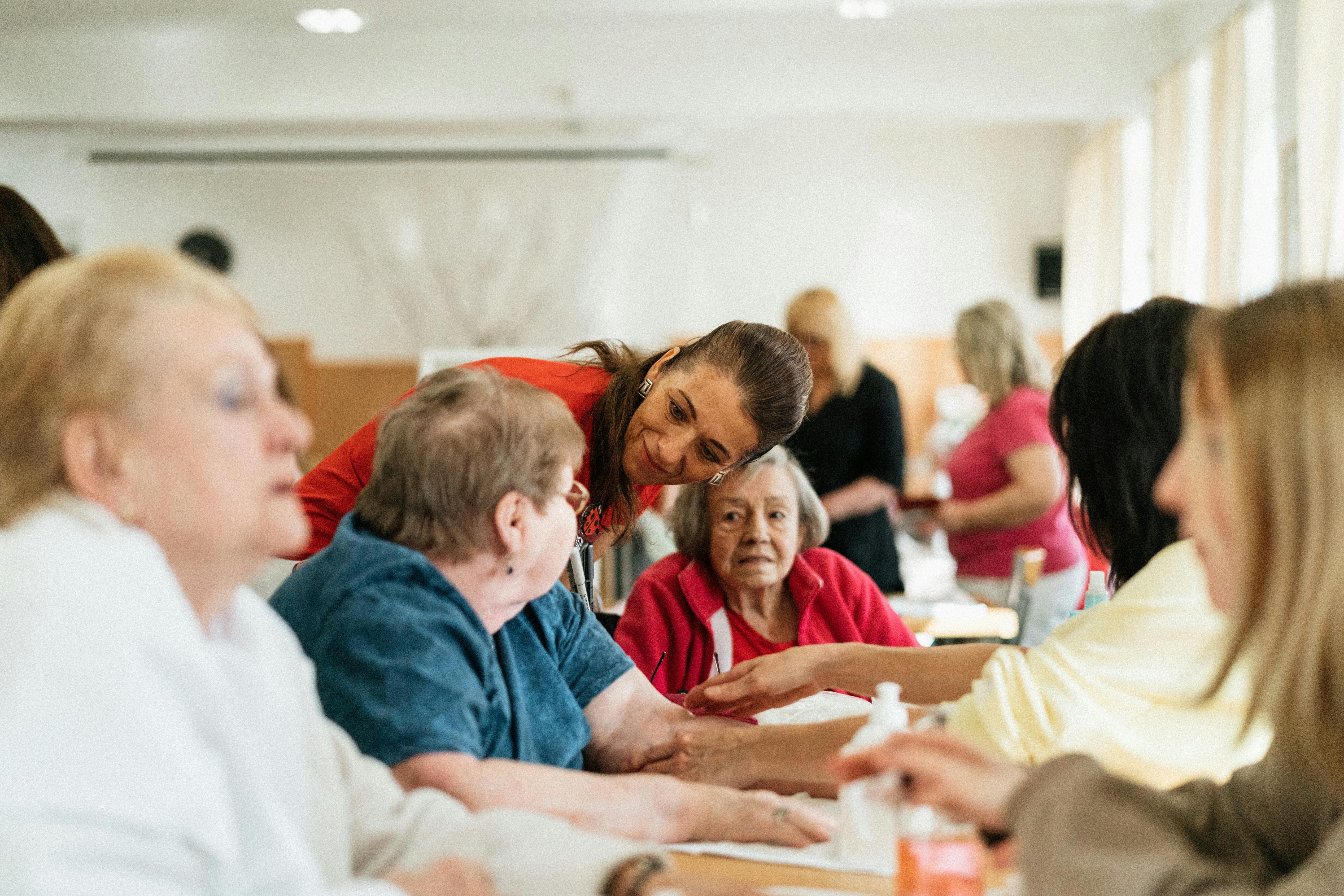 Caregiver assisting elderly residents at table