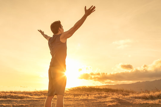 man standing out in the sunshine with his arms spread in gratitude.