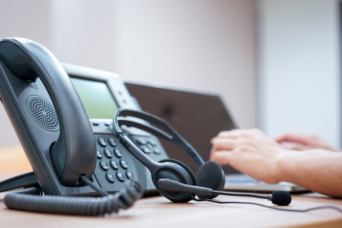 C&H Exteriors roofing contractor - a telephone with headset on the front of a desk