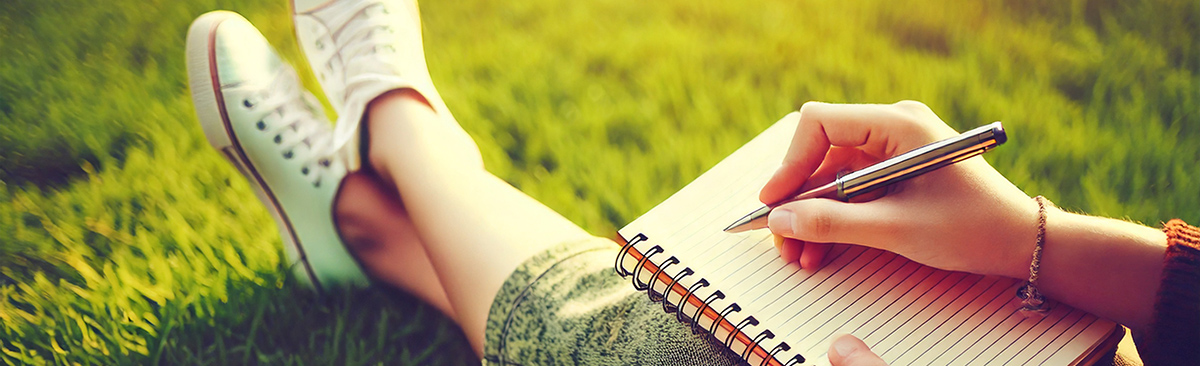 woman writing journal on grass woman writing journal on grass