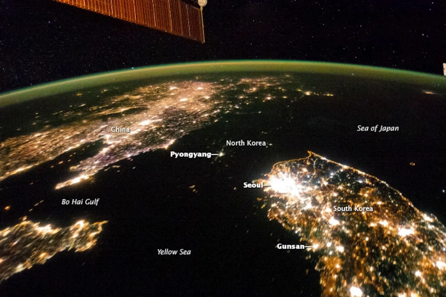 Satellite view of the Korean Peninsula at night — South Korea densely illuminated, North Korea in darkness — visual metaphor for how rich movement exposure builds a dense neural network in young athletes