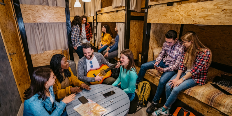 solo traveler chatting with new friends at a hostel common area solo traveler chatting with new friends at a hostel common area