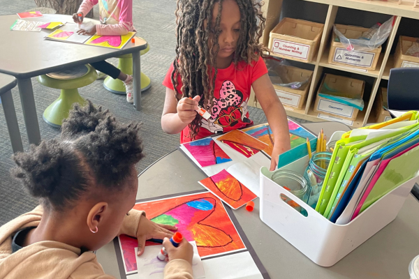 Two female students paint heart pictures to give to another student in the classroom to promote a caring environment. 