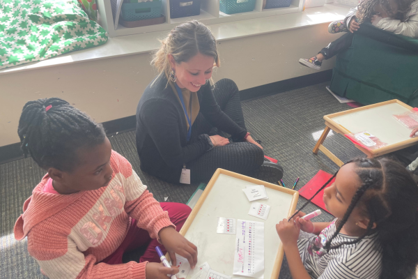 A teacher observes while two students play a math game they have chosen. 