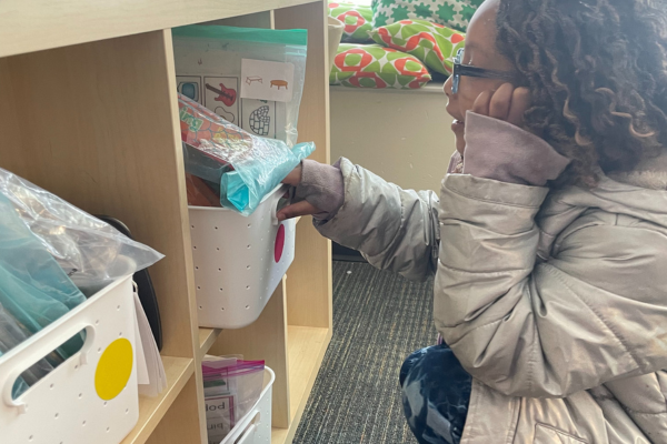 A student uses the colored-coding on the literacy bins to independently navigate the classroom and make a choice