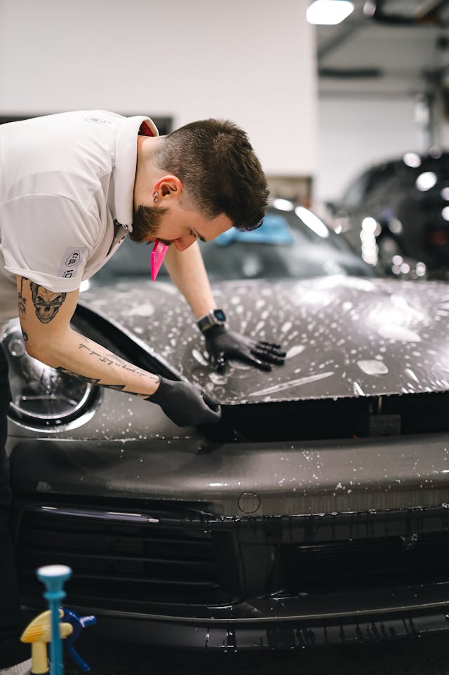 Professional technician applying SOVERLUX Paint Protection Film to luxury vehicle, ensuring invisible protection against scratches and road damage