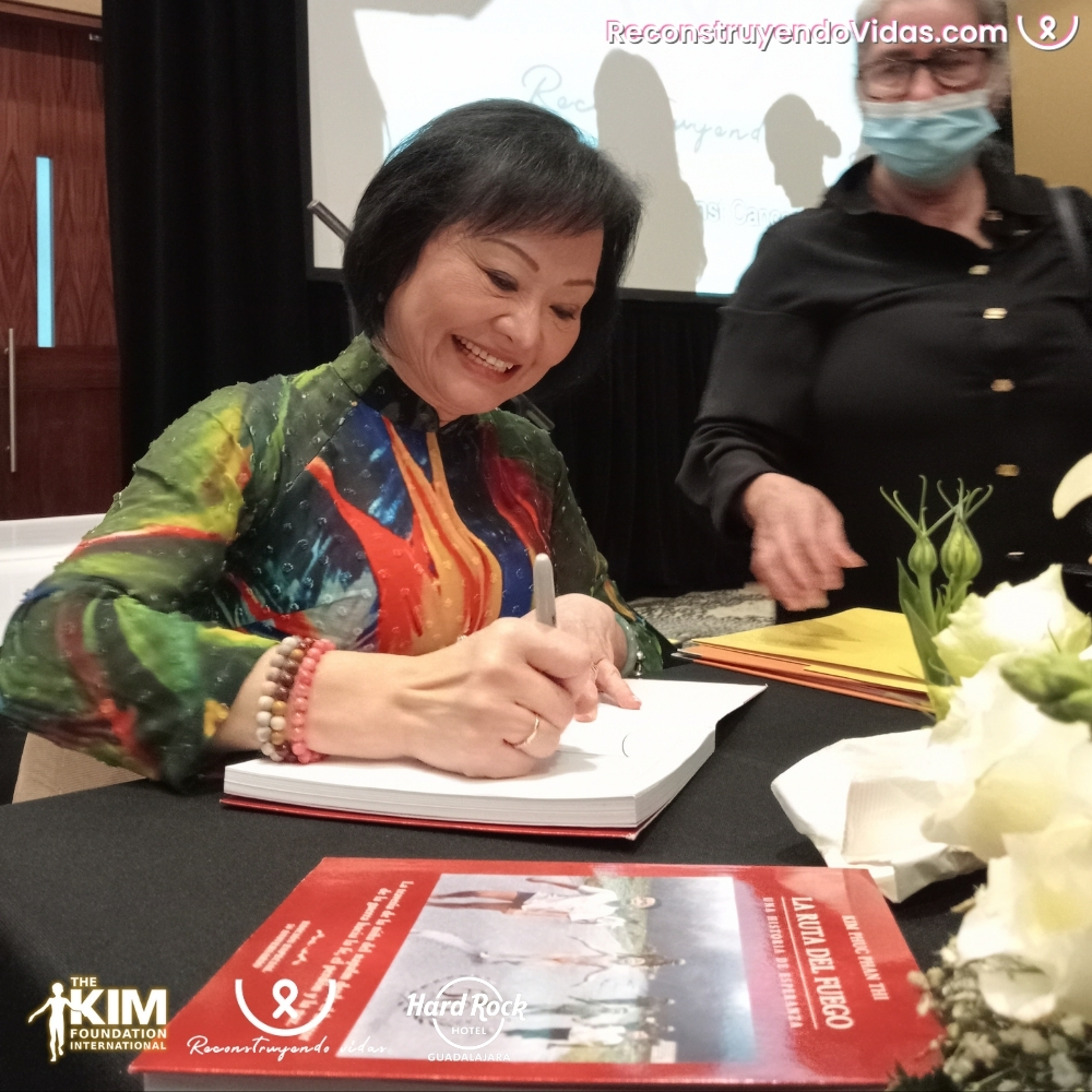 Kim Phuc firma libros durante la conferencia y desayuno en Guadalajara.