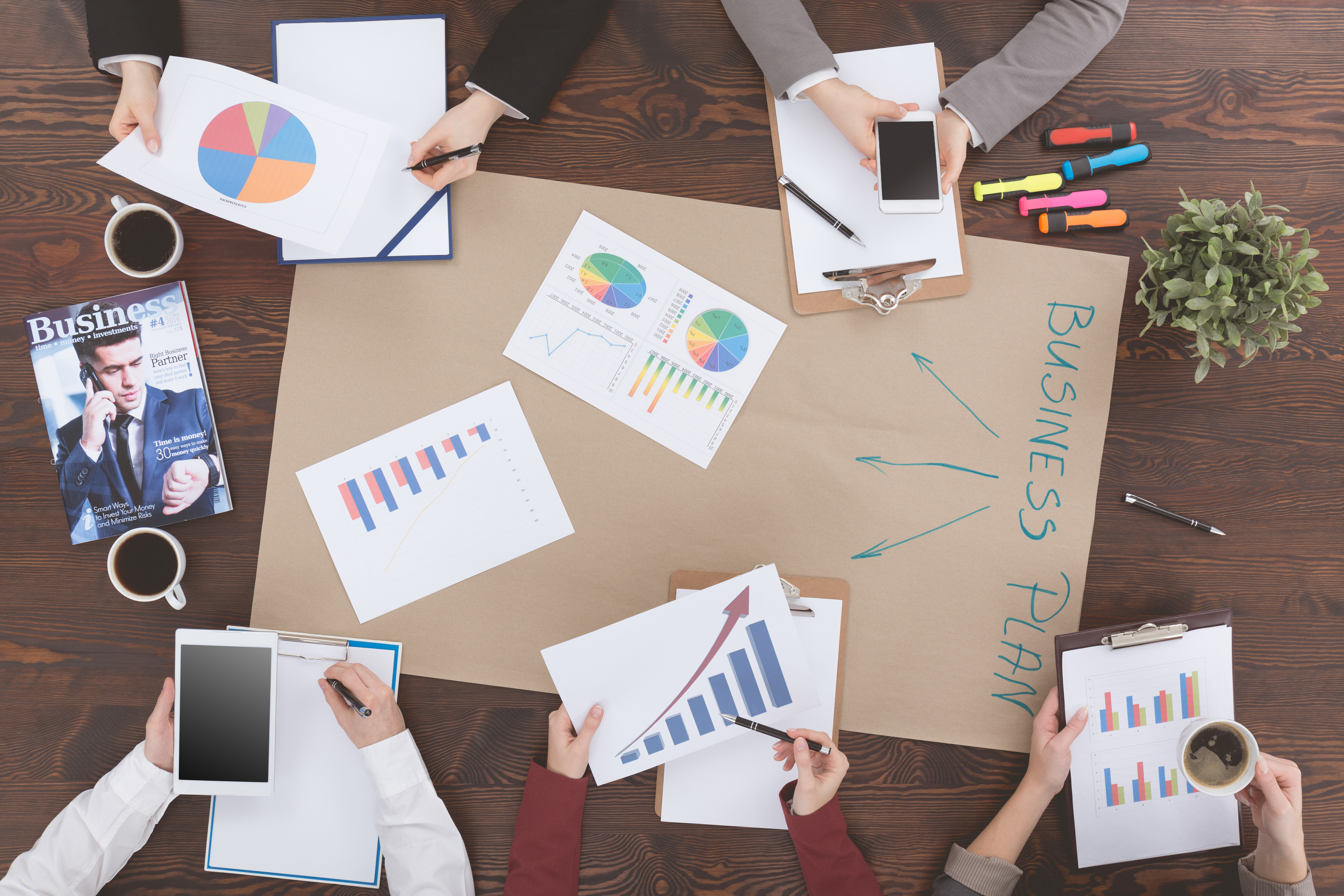multiple people gathered around documents and a business plan in the center