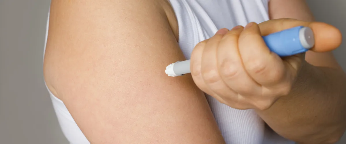 Person self-administering a weight loss injection in the arm