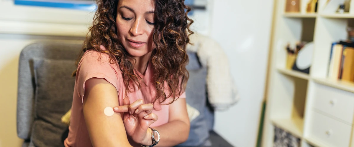 Woman applying a vitamin patch to her arm at home.