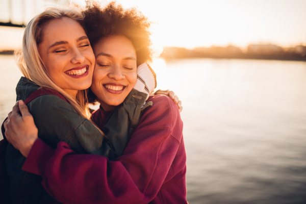 Two close friends sharing a warm hug while enjoying the outdoors, symbolizing the bond of friendship and connection.