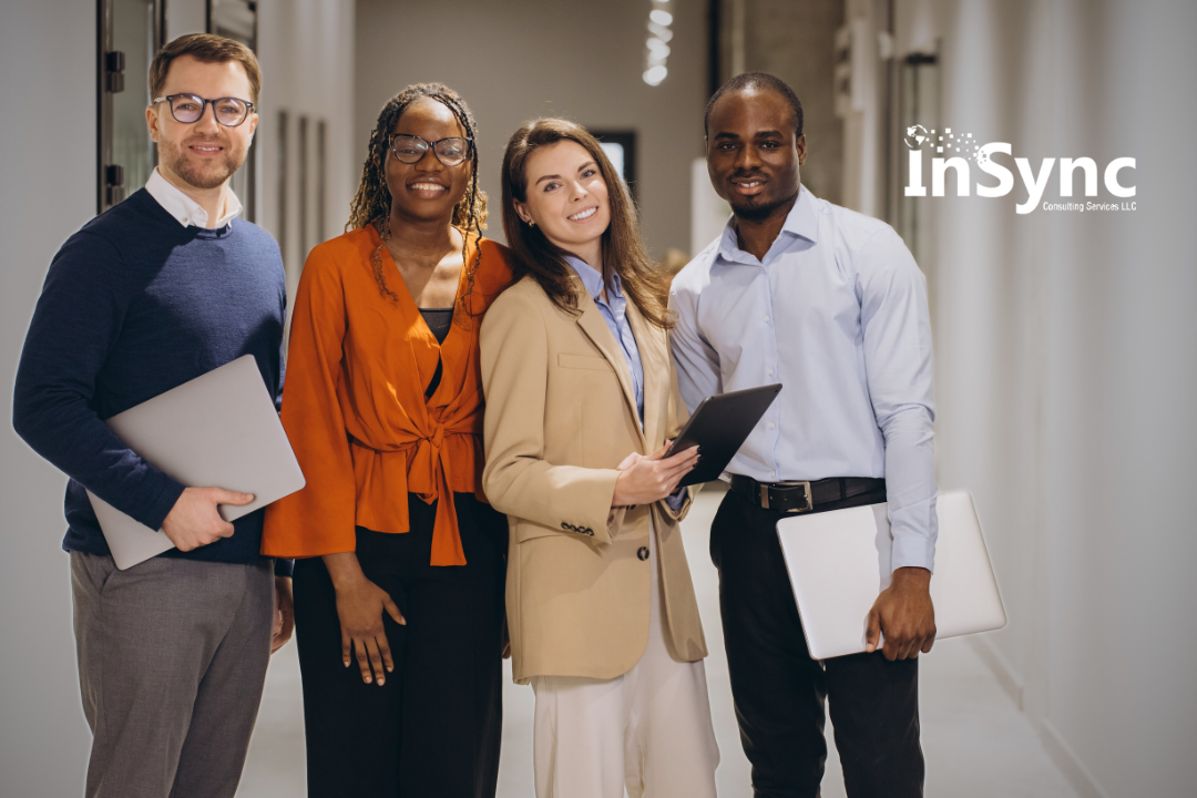 Group of four diverse professionals standing confidently in a modern office hallway, holding laptops and tablets, with the InSync Consulting Services LLC logo in the corner, representing unity and innovation in the workplace. 2/2 Group of four diverse professionals standing confidently in a modern office hallway, holding laptops and tablets, with the InSync Consulting Services LLC logo in the corner, representing unity and innovation in the workplace. 2/2