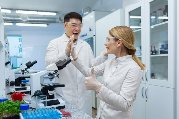 two lab techs high-five in celebration, having found solutions to analytical tool challenges
