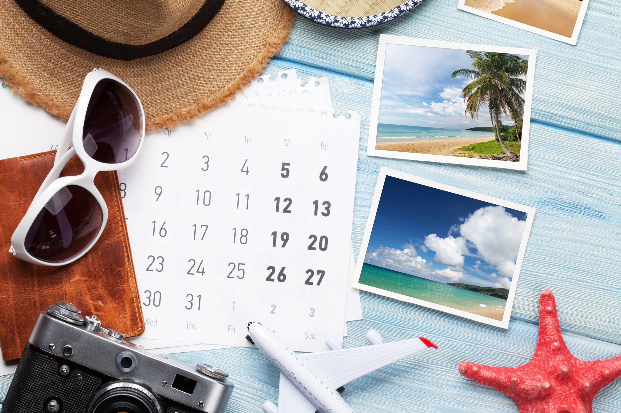 Table with a calendar, sunglasses, camera, sunglasses and holiday photos strewn about Table with a calendar, sunglasses, camera, sunglasses and holiday photos strewn about