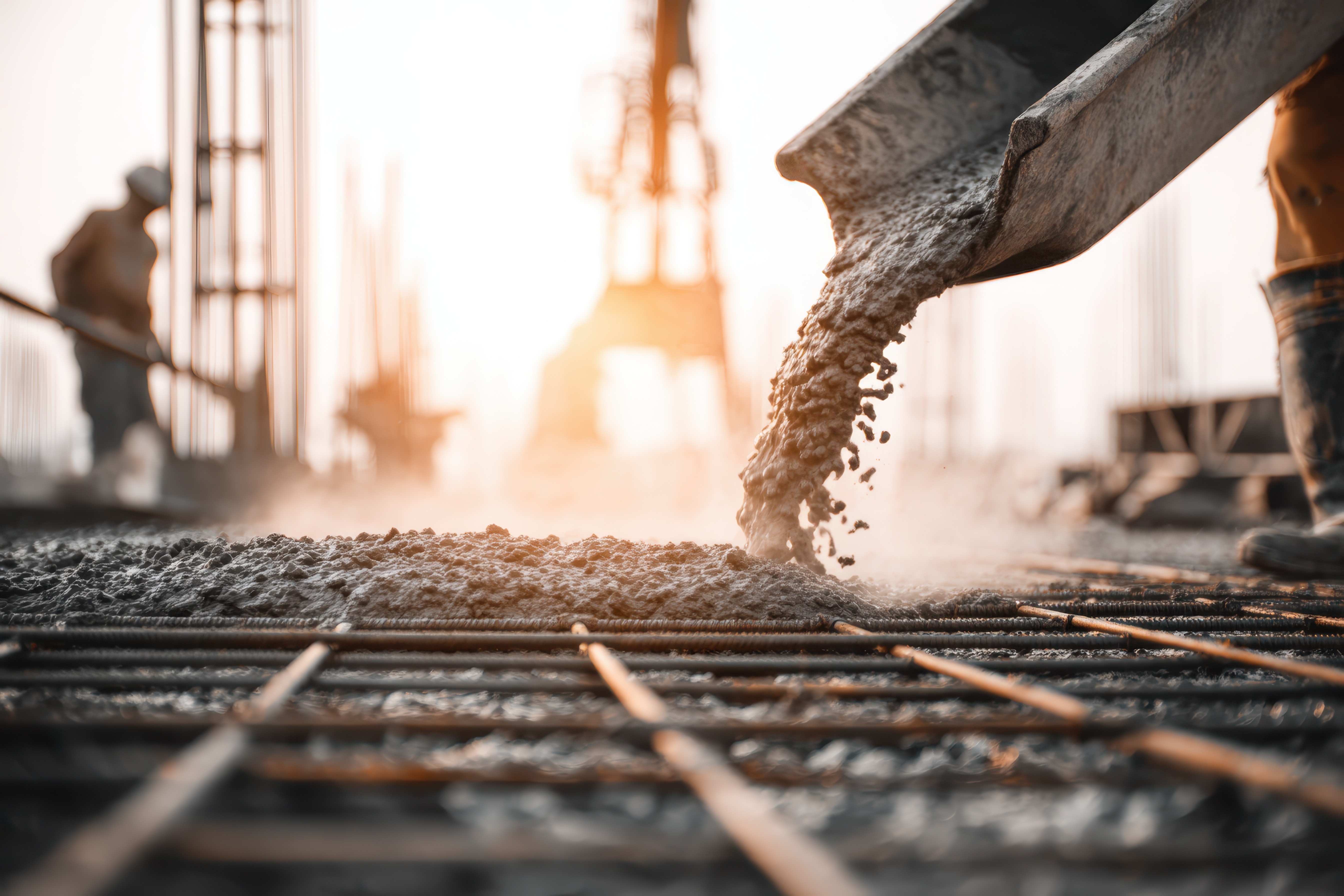 Construction worker pouring fresh concrete onto reinforced steel rebar for a foundation. Construction worker pouring fresh concrete onto reinforced steel rebar for a foundation.