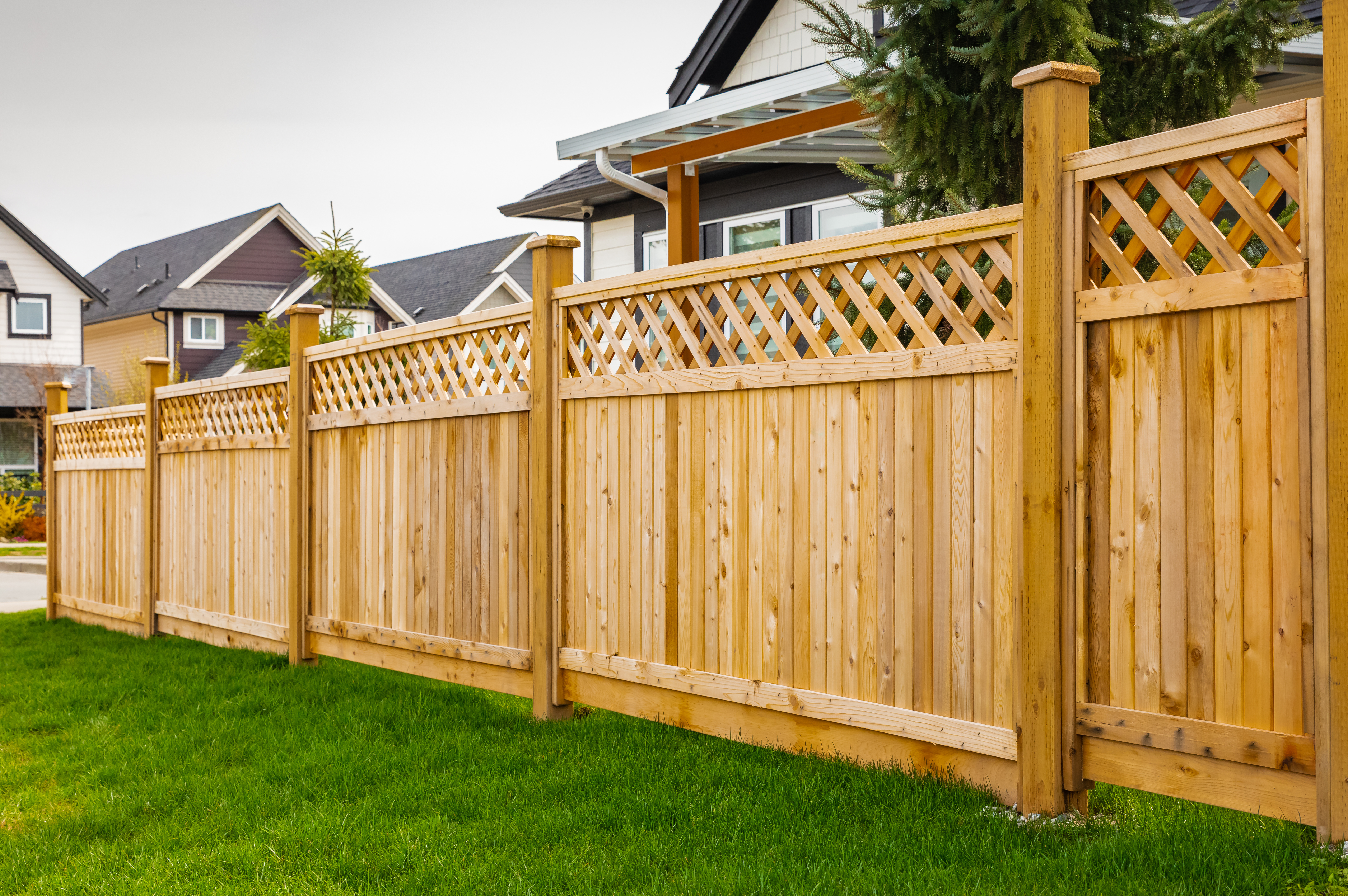 Wooden privacy fence installed in a residential backyard with decorative lattice panels.