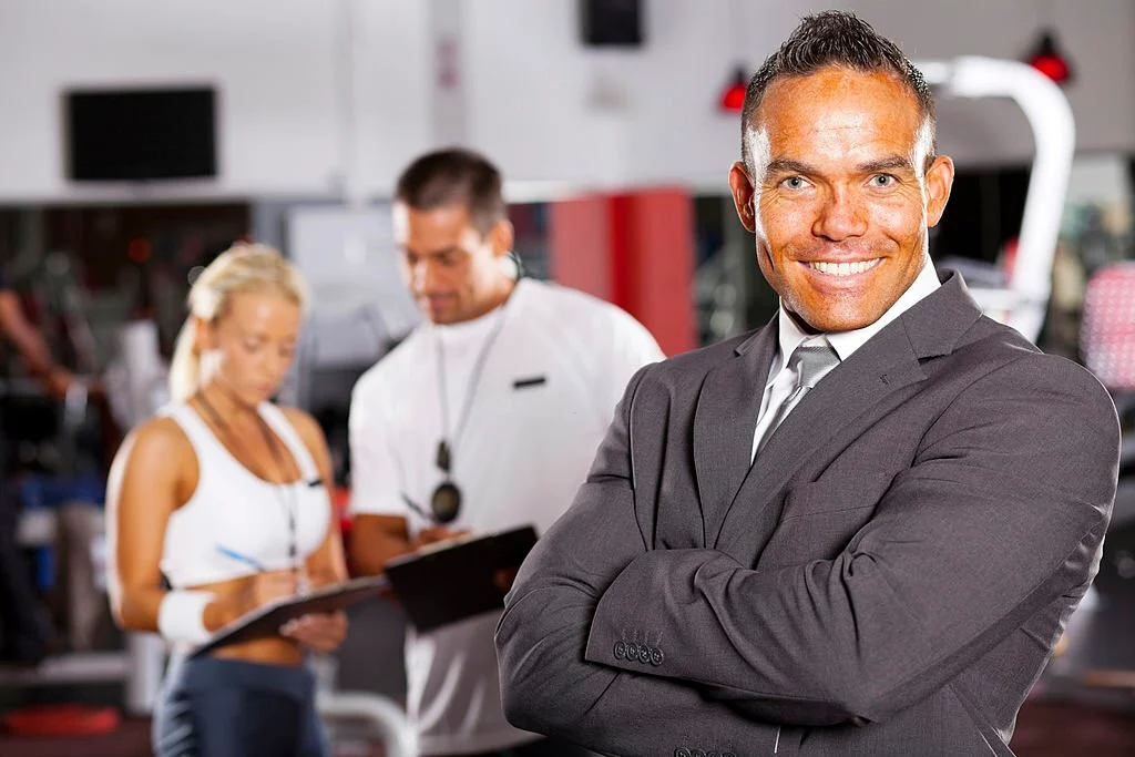 Một người chủ phòng gym đang nhìn chăm chú vào đội ngũ nhân viên của mình với vẻ mặt suy tư, biểu trưng cho việc tìm kiếm người kế nhiệm nội bộ. Một người chủ phòng gym đang nhìn chăm chú vào đội ngũ nhân viên của mình với vẻ mặt suy tư, biểu trưng cho việc tìm kiếm người kế nhiệm nội bộ.