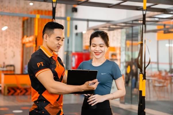 Nhân viên tư vấn phòng gym giới thiệu gói huấn luyện viên cá nhân (PT) cho khách hàng mới tại quầy đăng ký, nhấn mạnh điểm bán hàng hiệu quả và tận dụng thời điểm vàng. Nhân viên tư vấn phòng gym giới thiệu gói huấn luyện viên cá nhân (PT) cho khách hàng mới tại quầy đăng ký, nhấn mạnh điểm bán hàng hiệu quả và tận dụng thời điểm vàng.