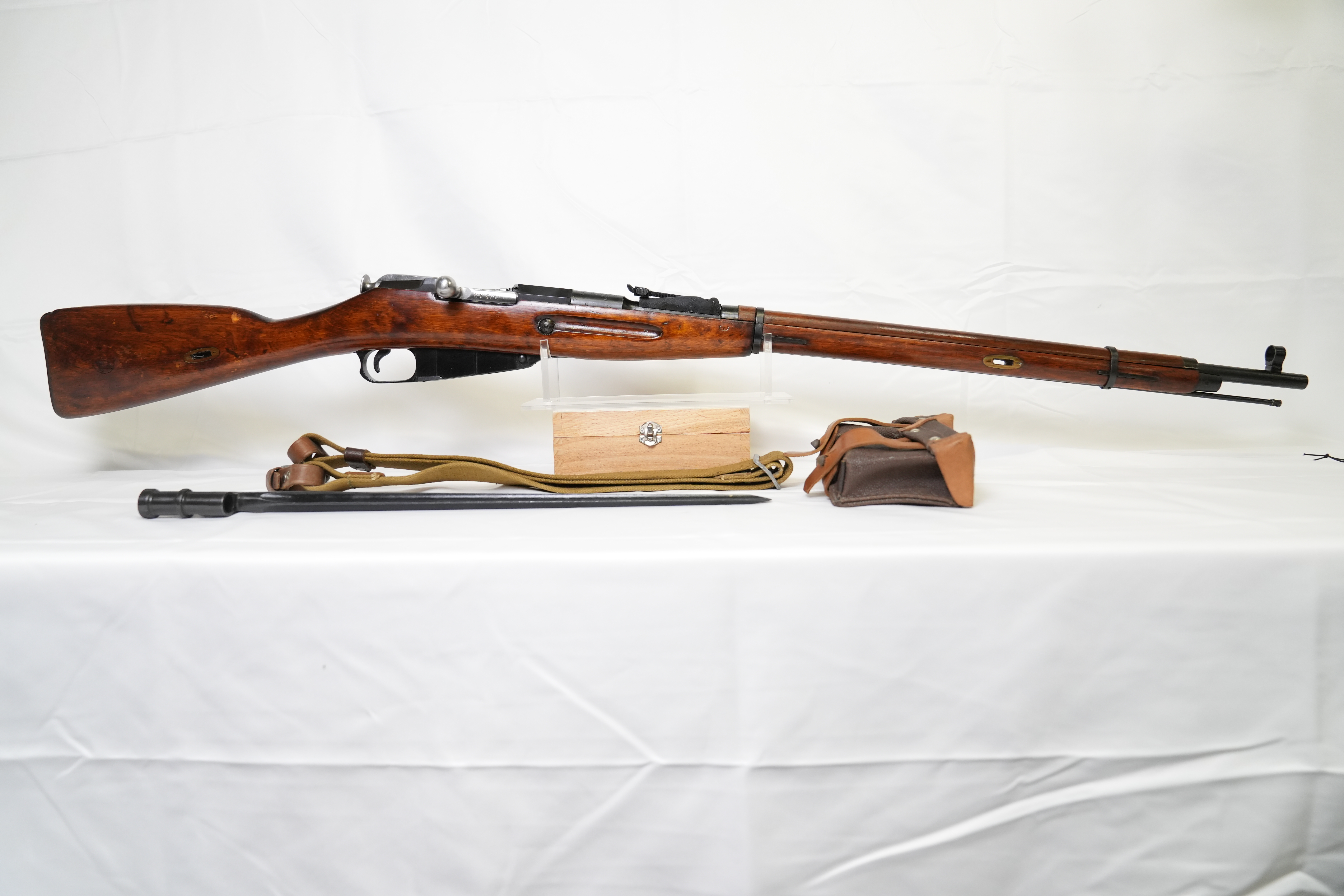 Historic Soviet M91/30 Mosin-Nagant rifle displayed with original accessories, including bayonet, sling, ammunition pouch, and cleaning kit on a white background. Historic Soviet M91/30 Mosin-Nagant rifle displayed with original accessories, including bayonet, sling, ammunition pouch, and cleaning kit on a white background.