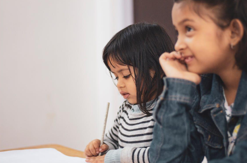 Two young girls joyfully engaged in creative learning indoors Two young girls joyfully engaged in creative learning indoors