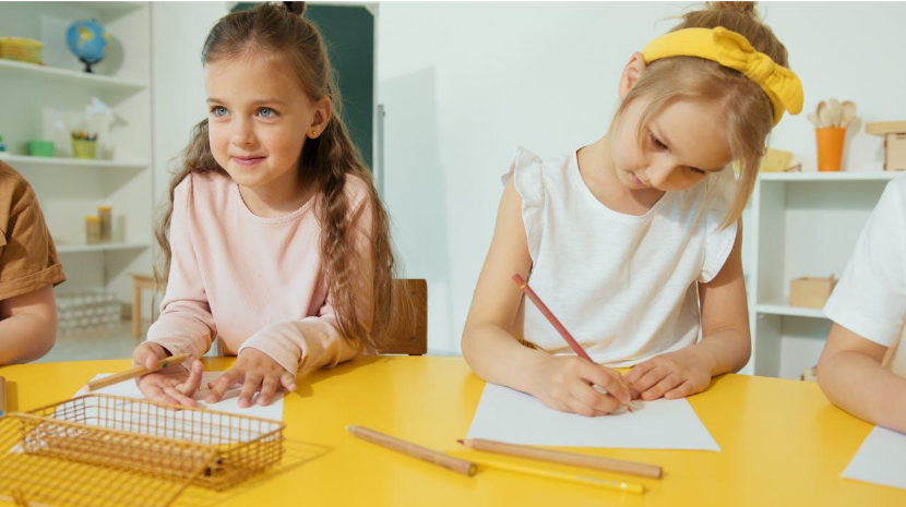 Two young girls writing and learning in a bright classroom setting Two young girls writing and learning in a bright classroom setting