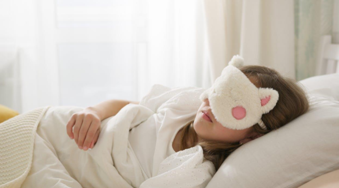 A child peacefully sleeping with a cozy animal-themed sleep mask in a bright bedroom. A child peacefully sleeping with a cozy animal-themed sleep mask in a bright bedroom.